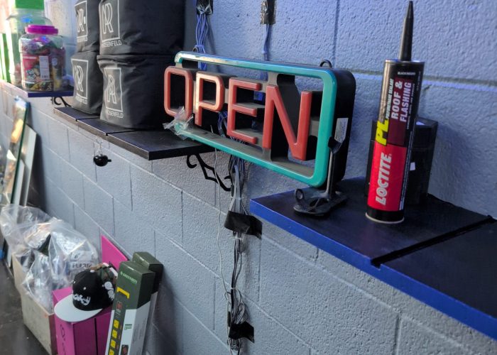 Glowing neon open sign against gray block wall